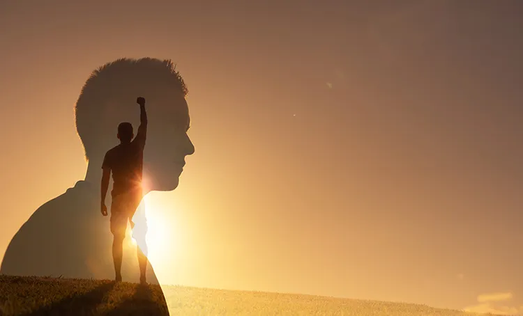 a man stands at the top of a hill with his fist raised and a reflection of his face overlaying the figure