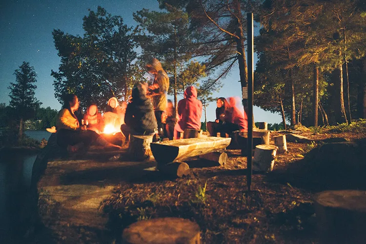 Teenagers sit around a campfire