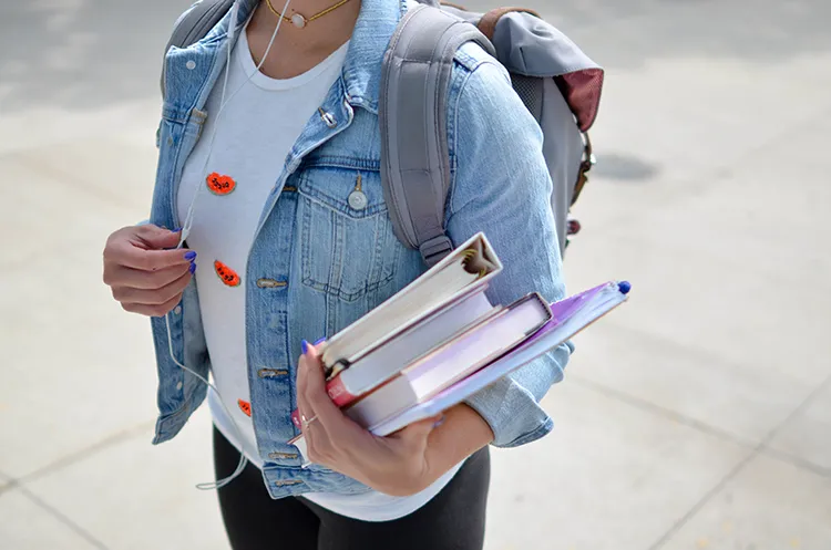 Student carries a backpack and books