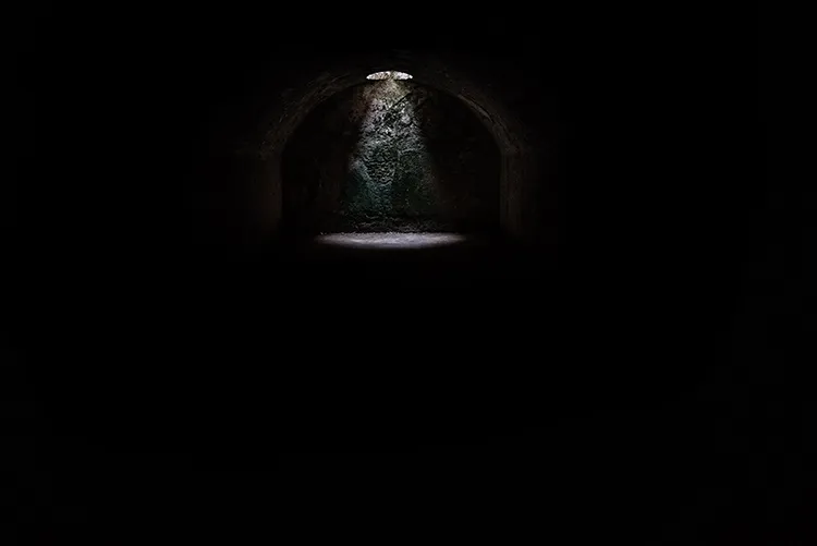 a light shines down through a hole in a dark cave