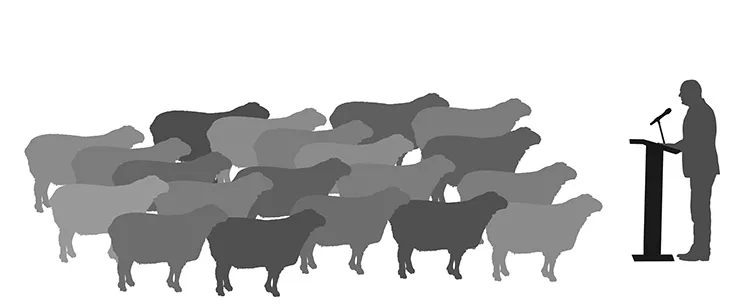 crowd of sheep stand before a man speaking at a podium