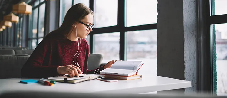 female student listening to music while reading a book