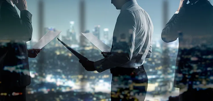 businessmen looking over files with the city landscape in the background