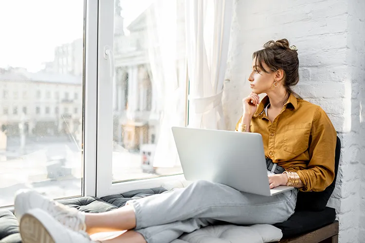 woman working on her laptop and looking out the window