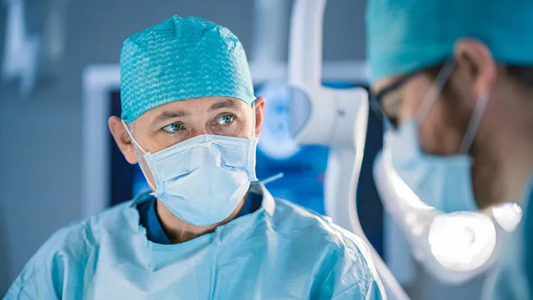 view from below of three surgeons with scalpels performing an operation