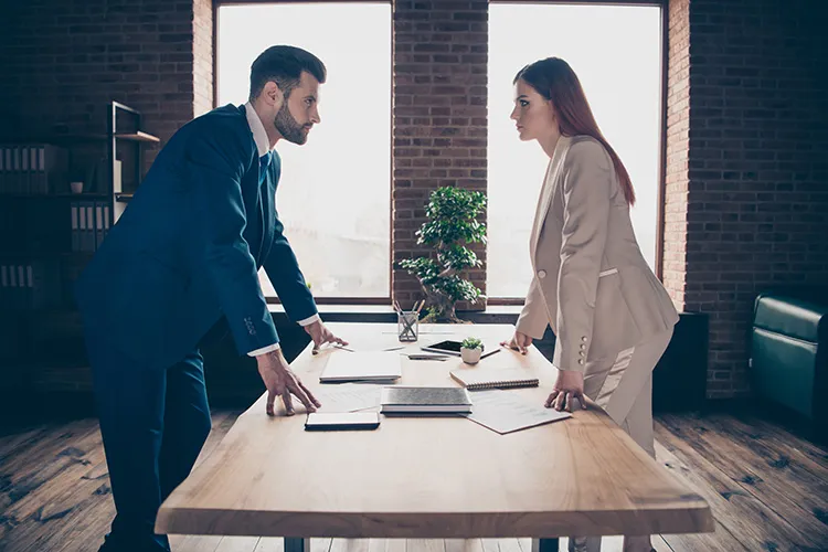 male and female colleagues staring each other down in an office setting