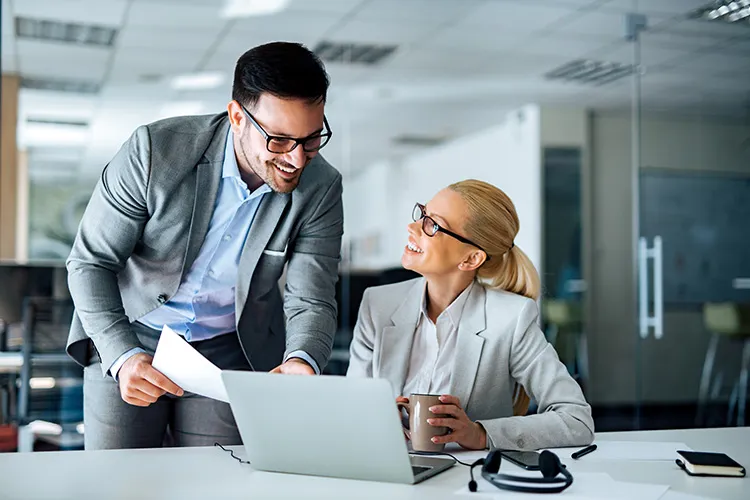 male and female work colleagues smile while working together on an assignment