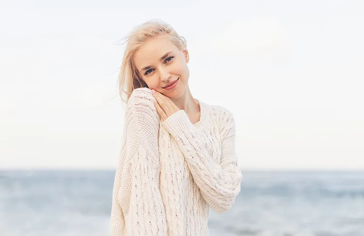 blond woman smiling with the ocean in the background