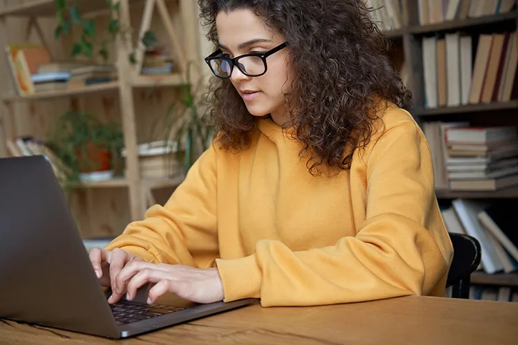 teenage girl types on her laptop