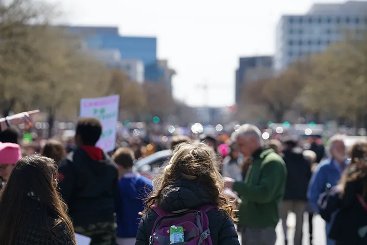 student stands in front of a protest