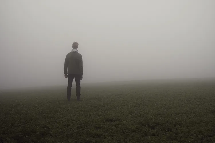 Man standing in a foggy field