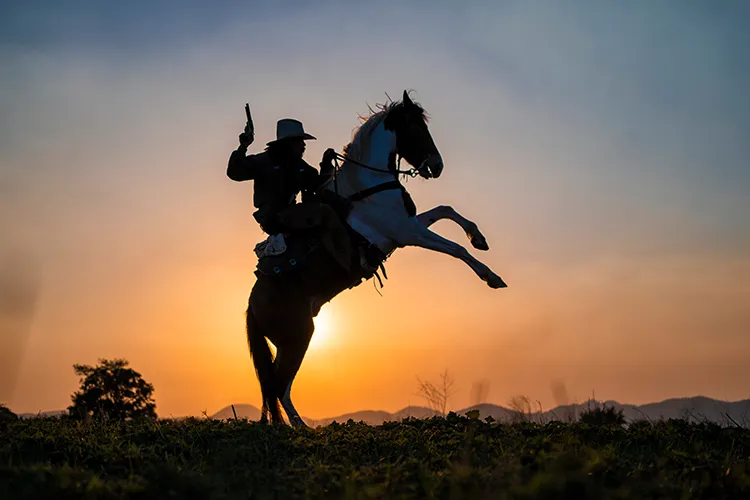 A cowboy with a gun riding a horse